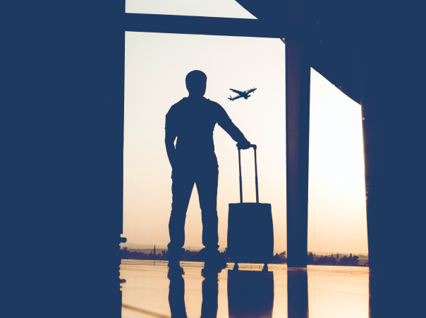 Man standing with luggage in airport window.